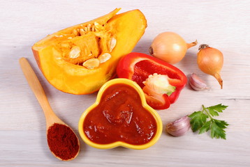 Sauce of pumpkin in glass bowl and ingredients on wooden table