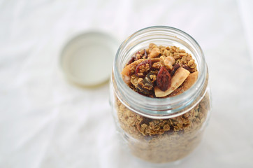 Homemade granola with dried fruits and coconut flakes in a glass jar
