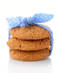 Stack of three homemade oatmeal cookies tied with blue ribbon in small white polka dots, isolated on white background
