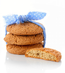 Stack of three homemade oatmeal cookies tied with blue ribbon in small white polka dots and half of cookie, isolated on white background