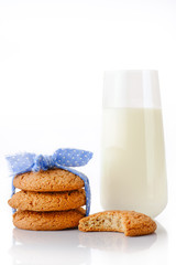 Stack of three homemade oatmeal cookies tied with blue ribbon in small white polka dots, bitten cookie and glass of milk, isolated on white background