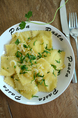 Ravioli garnished with parsley served on a plate with pasta word