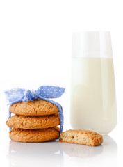 Stack of three homemade oatmeal cookies tied with blue ribbon in small white polka dots, half of cookie and glass of milk, isolated on white background