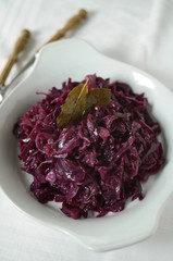 Stewed red cabbage served on a white plate with bay leaves