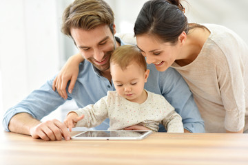 Parents with baby girl playing with digital tablet