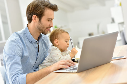 Busy businessman working from home and watching baby