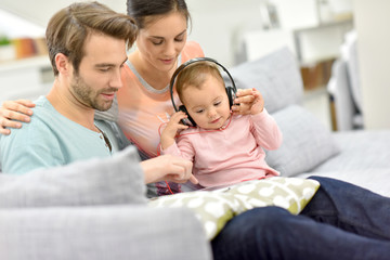 Fototapeta premium Couple with baby in sofa watching movie on tablet