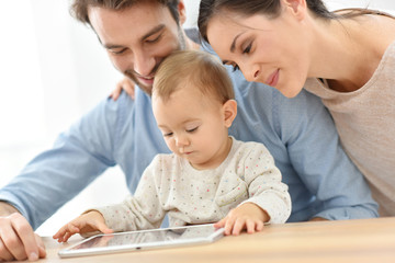 Parents with baby girl playing with digital tablet