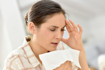 Young woman with cold blowing her nose