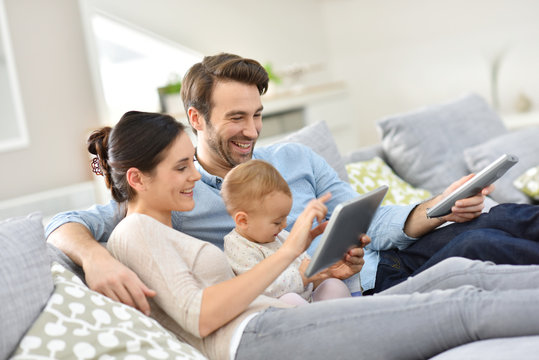 Family With Baby In Sofa Watching Tv