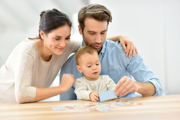 Obraz na płótnie Canvas Parents with baby girl playing cards