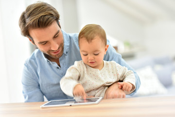 Man with baby looking at digital tablet