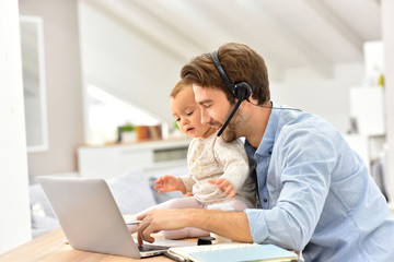 Busy businessman working from home and watching baby