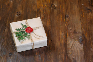 gift wrapped in kraft paper, tied with string and glued wax seal. Lying on the table.