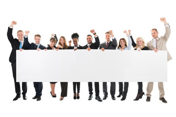 Obraz premium Happy Business Team With Arms Raised Holding Blank Billboard
