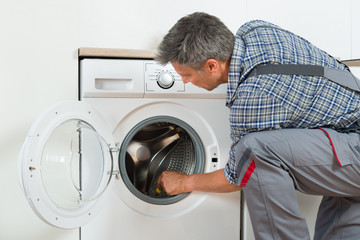 Repairman Checking Washing Machine At Home