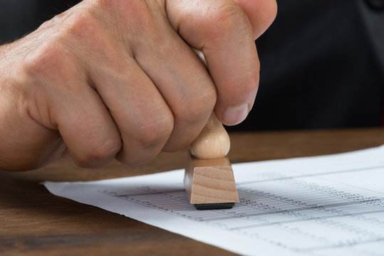 Businessman Stamping Document At Desk