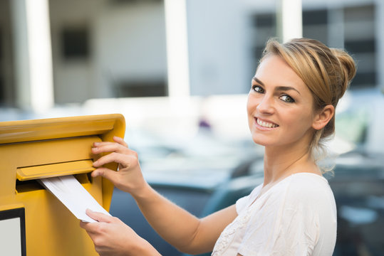 Woman Inserting Letter In Mailbox