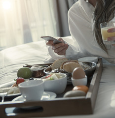 Breakfast in bed in an hotel in the morning and checking emails