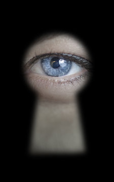 Female eye peeking through a keyhole