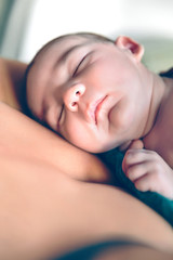 Obraz na płótnie Canvas Newborn baby sleeping peacefully over the mother chest