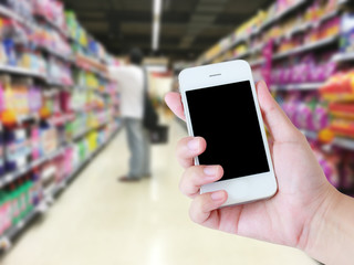 Hand holding mobile phone with blank screen with blur supermarke
