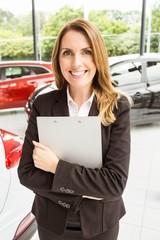 Smiling saleswoman holding document while looking at camera
