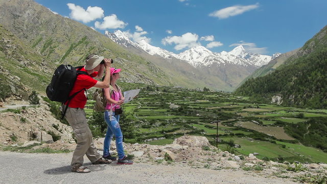Hikers trekkers read a trekking map on trek in Himalayas mountains. Himachal Pradesh,India