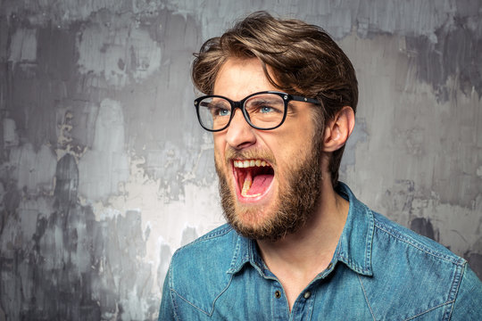 Young man screaming with widely opened mouth