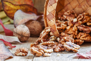 Fresh walnuts spill out of a wicker basket on autumn background