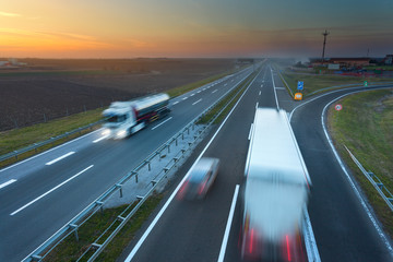 Obraz premium Many trucks in motion blur on the motorway at sunset