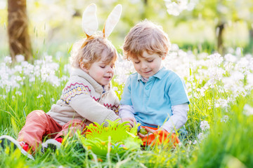 Two funny children friends in Easter bunny ears during egg hunt