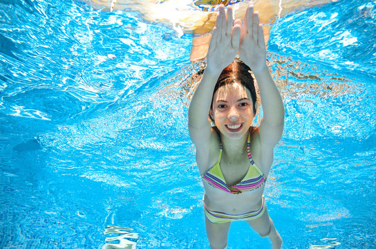 Child swims in pool underwater, happy active girl has fun in water, kid sport on family vacation

