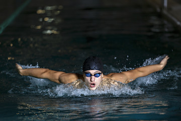 dynamic and fit swimmer in cap breathing performing the butterfl