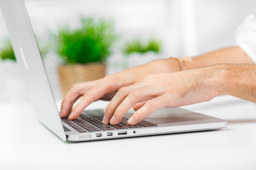 Cropped shot of a man's hands using a laptop at home