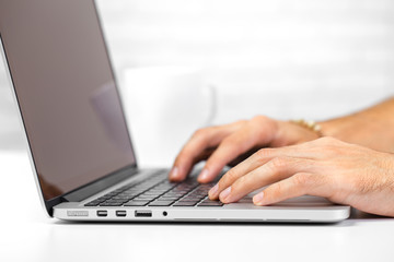 Cropped shot of a man's hands using a laptop at home