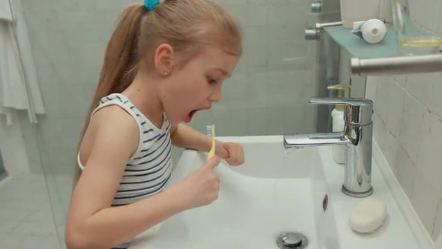 Girl carefully brushing his teeth after eating