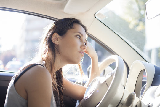 Portrait Of Tired Woman Driving Car And Looking Through Window