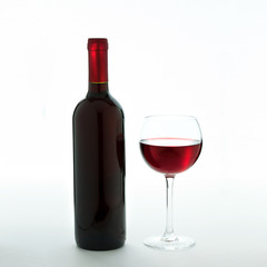 Glass and bottle of red wine unusually on white background.