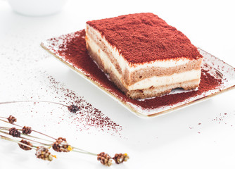 Tasty tiramisu cake with coffee beans on white