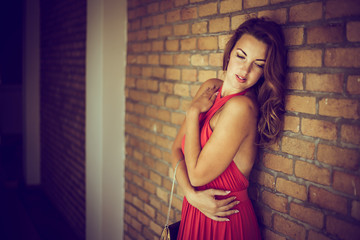 beautiful young lady in red posing near brick wall