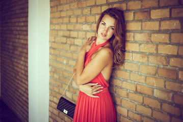 beautiful young lady in red posing near brick wall