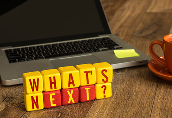 Whats Next? written on a wooden cube in a office desk