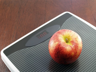 apple on grey digital weight scale on wooden floor, diet inspiration concept for weight control by eating fruit