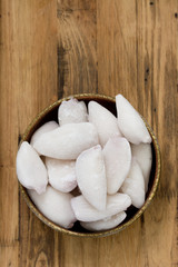 frozen squids in dish on brown wooden background