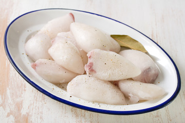 frozen squids in dish on white wooden background