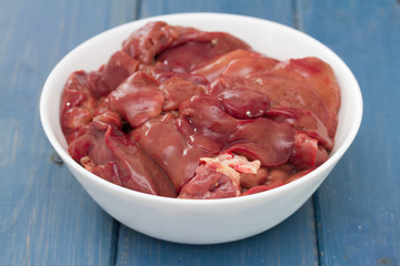 chicken liver in white bowl on blue wooden background