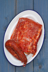 smoked sausage with meat on white dish on blue wooden background