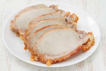 baked pork on white plate on white wooden background
