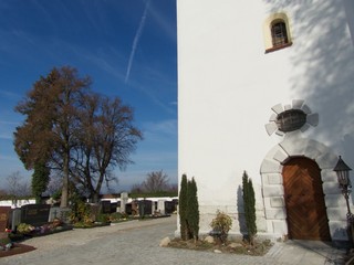 Der Friedhof an der Pfarrkirche Sankt Cosmas und Damian bei blauem Himmel und Sonnenschein in Markt Burgheim im Landkreis Neuburg-Schrobenhausen in Oberbayern